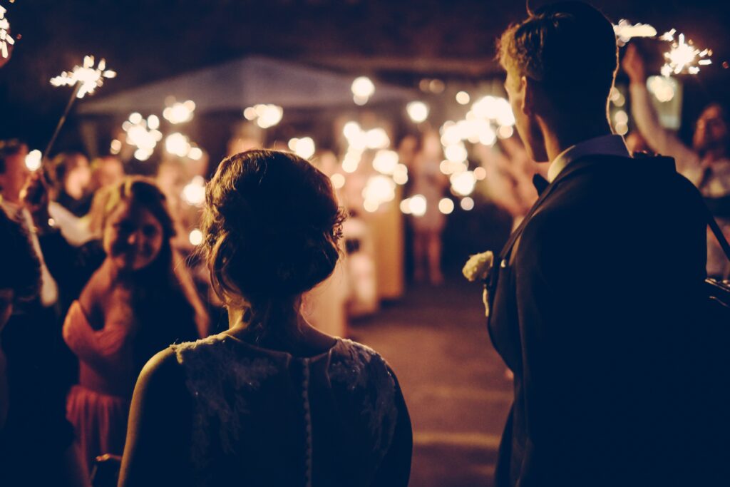 Guests holding sparklers under warm string lights at an evening tent reception